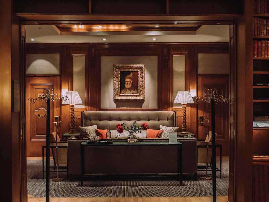 Wood-panelled hotel lounge with leather seating, warm lamps and framed artwork