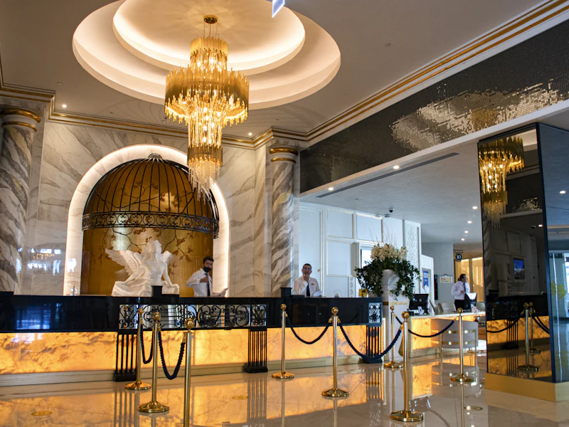 Hotel reception desk beneath a chandelier, with staff behind a glowing marble counter