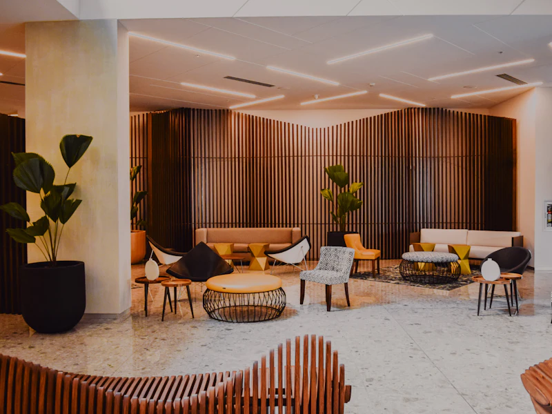 Open-plan hotel lounge with timber slat walls, plants and groups of armchairs