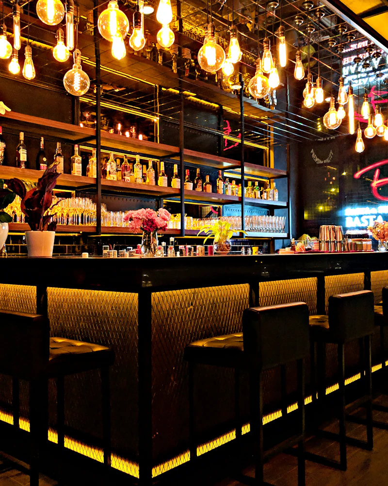 Backlit bar counter with warm pendant lights and shelves of bottles