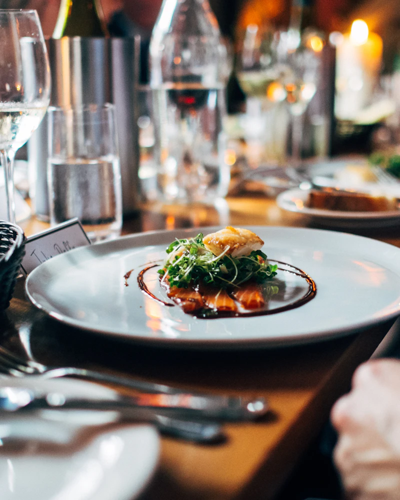 Plated dish served at a set table with glassware, bread and cutlery