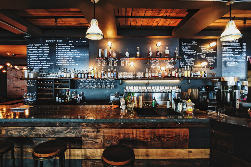 Long bar with pendant lights, a chalkboard menu and shelves of bottles