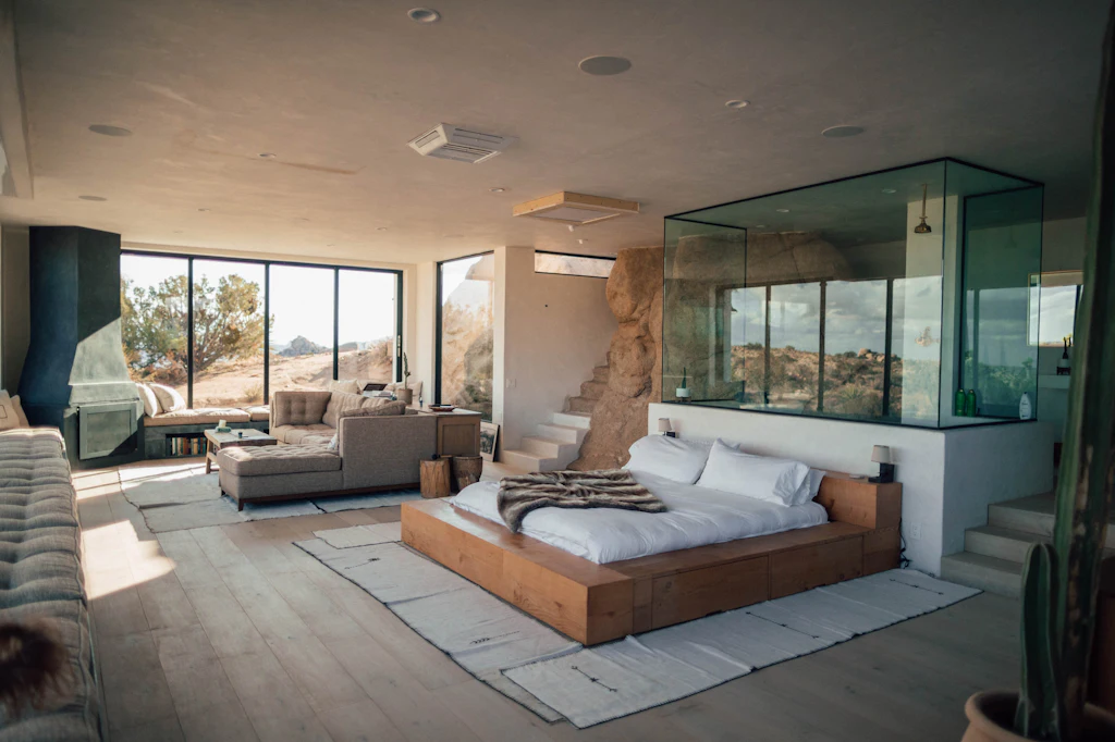 Spacious suite with a low bed, lounge seating and a glass-walled bathroom